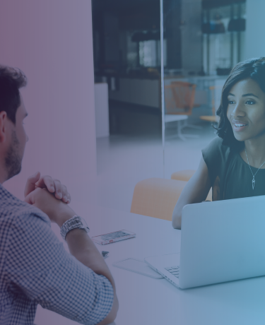Dos adultos teniendo una conversación mientras interactúan con una computadora portátil